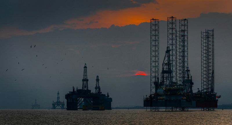 Offshore oil rigs in the sea against a red sunset.