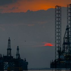 Offshore oil rigs in the sea against a red sunset.
