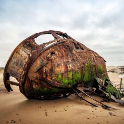 Ship Wreck along the Skeleton Coast in Western Namibia taken in January 2018; carcass of a ship with green bilge on the bottom lying on its side on a beach