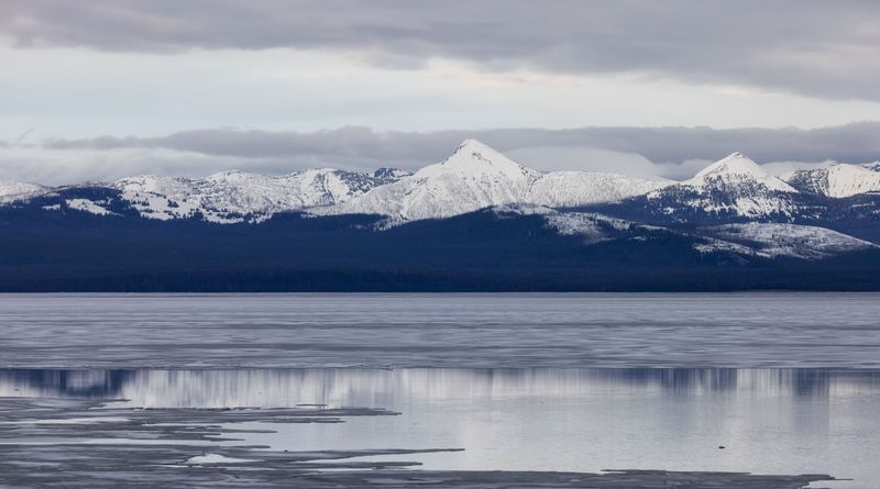 Yellowstone Lake frozen over with snow covered mountains behind