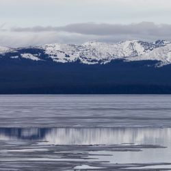 Yellowstone Lake frozen over with snow covered mountains behind