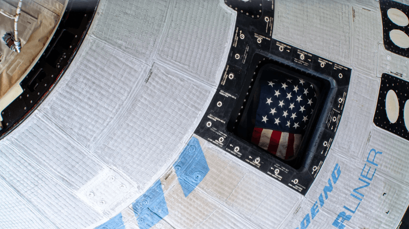 A photo of a portion of starliner showing in one of its windows the american flag